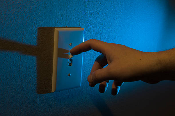 Male hand turning off the lights at night with finger.